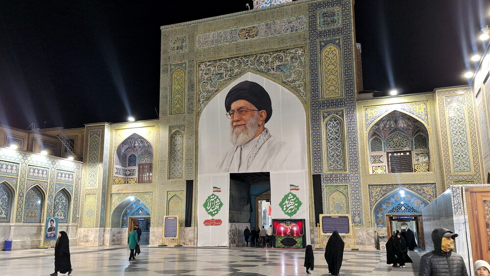 Since its founding in 1979, the IRGC has evolved from revolutionary militia to military force, then to an ideological-security cartel and a “state within the state”—and now, under the pressures of war and a looming succession crisis, into something close to the state itself. Each crisis handed the Guard a new mission, new resources, and greater autonomy. The result is its hardening around its most coercive institution. Image: large memorial banner featuring the late Supreme Leader Ayatollah Ali Khamenei at an entrance of the Imam Reza Holy Shrine, Mashhad, Iran; March 13, 2026.