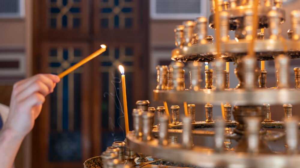 A worshiper lights prayer candles in a Greek Orthodox church.