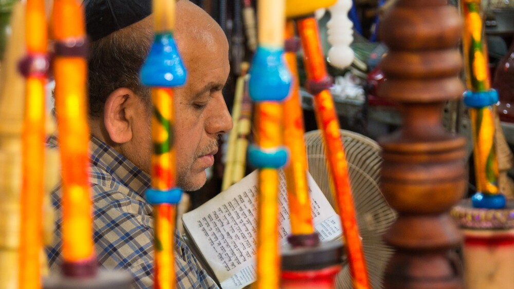 A Jewish water pipe seller reads the Torah in his shop in the Shiraz bazaar.