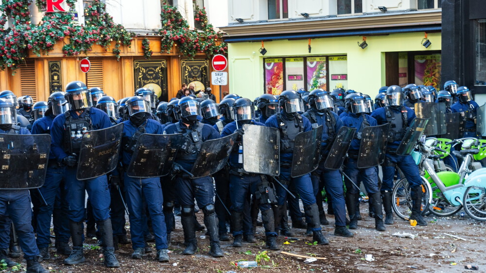 French riot police form a shield wall on a debris-strewn street near the Place de la Bastille in Paris, October 8, 2026, as rioting broke out on the edges of high-school student protests.