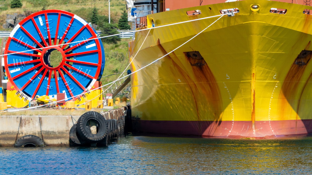Taunting Washington ahead of the midterm elections, the theocratic regime is attempting to leverage global digital infrastructure as a geopolitical shield. Bulk sub-sea industrial glass fiber optic cable on a metal spool on a ship's stand.