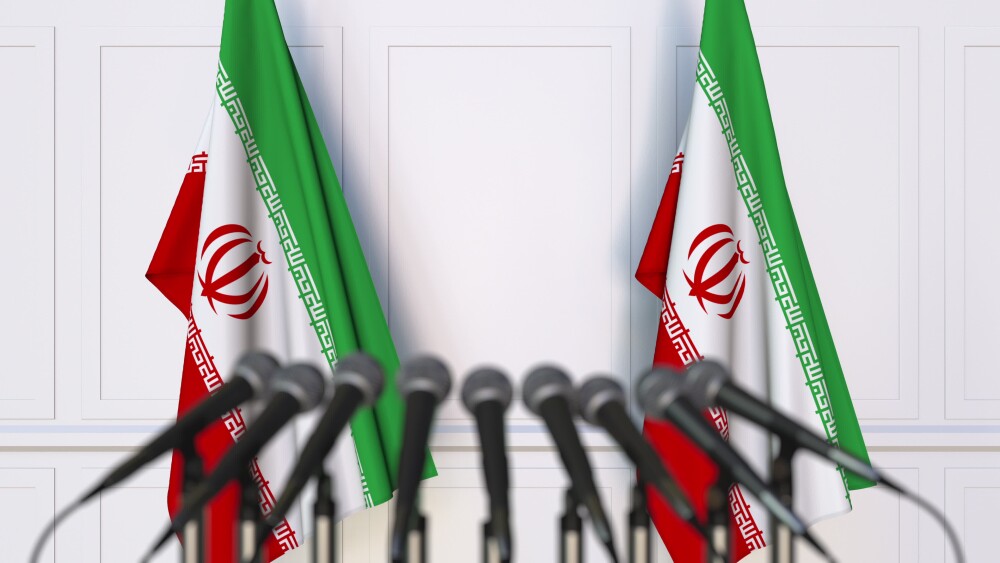 Iranian flags are posted at a podium set up for a news conference.