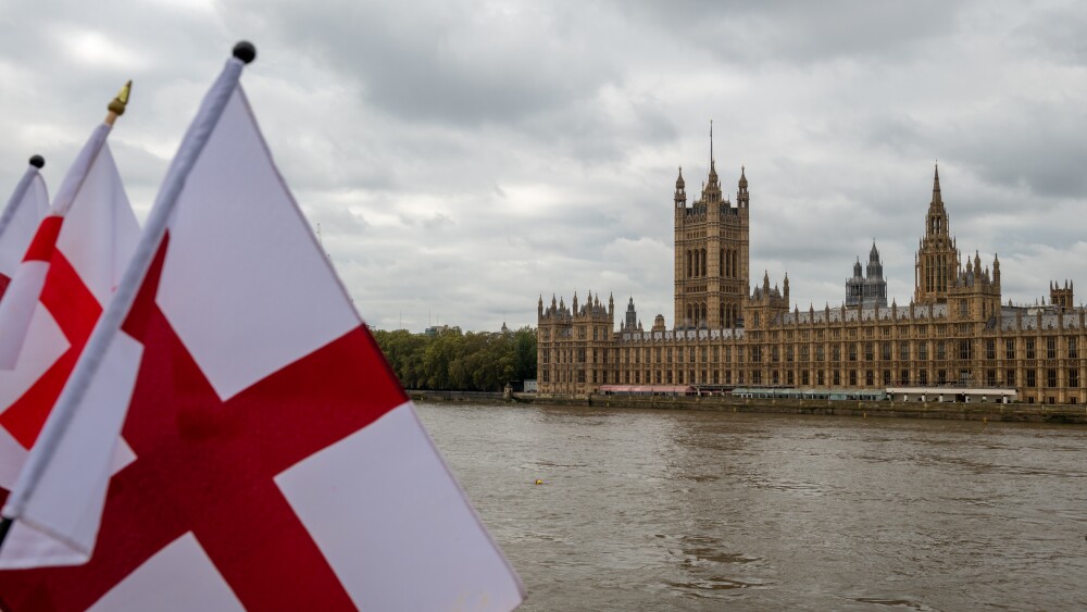 The flag of St. George files across the Thames from the Houses of Parliament in London. For those flying it today, the flag represents pride in being English—reclaiming a symbol of national unity, heritage, and patriotism.