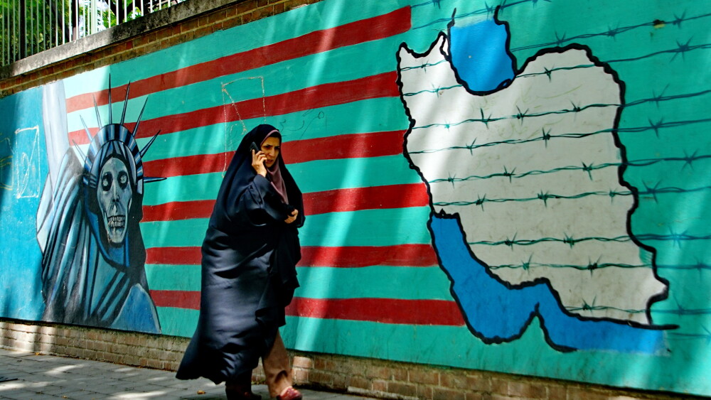 A woman walks past an anti-America mural on a wall in Tehran.